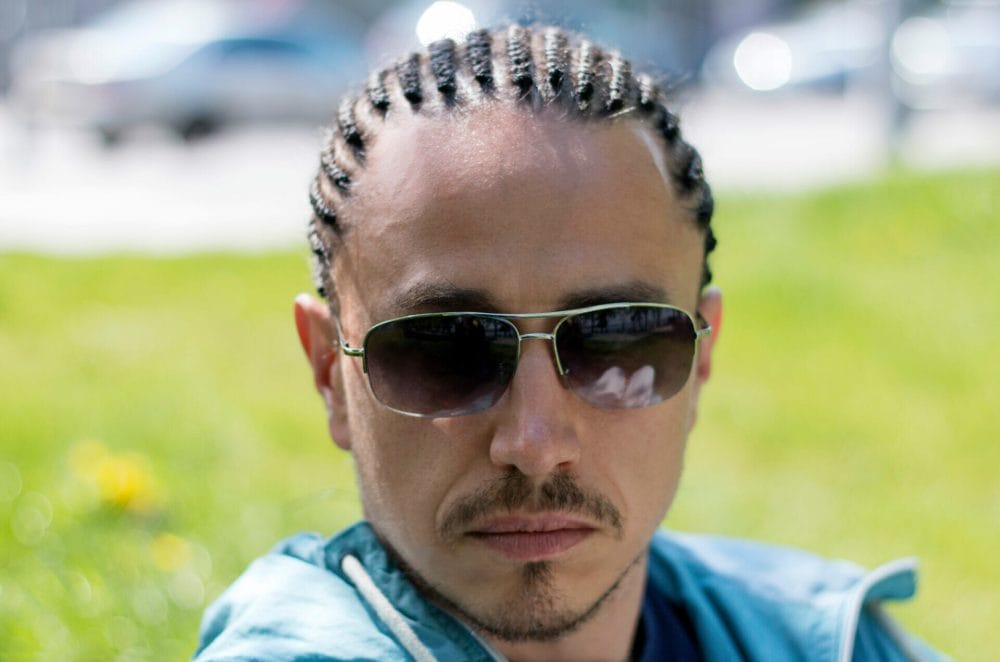 man with cornrows hairstyle knotless braids, wearing sunglasses in daylight